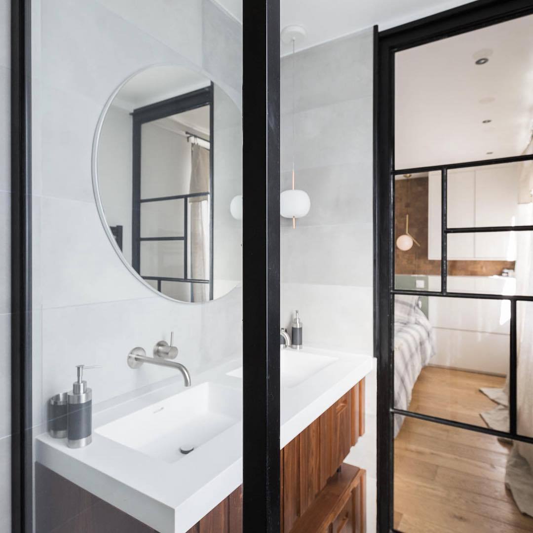 Salle d'eau avec miroir rond et cloison vitrée