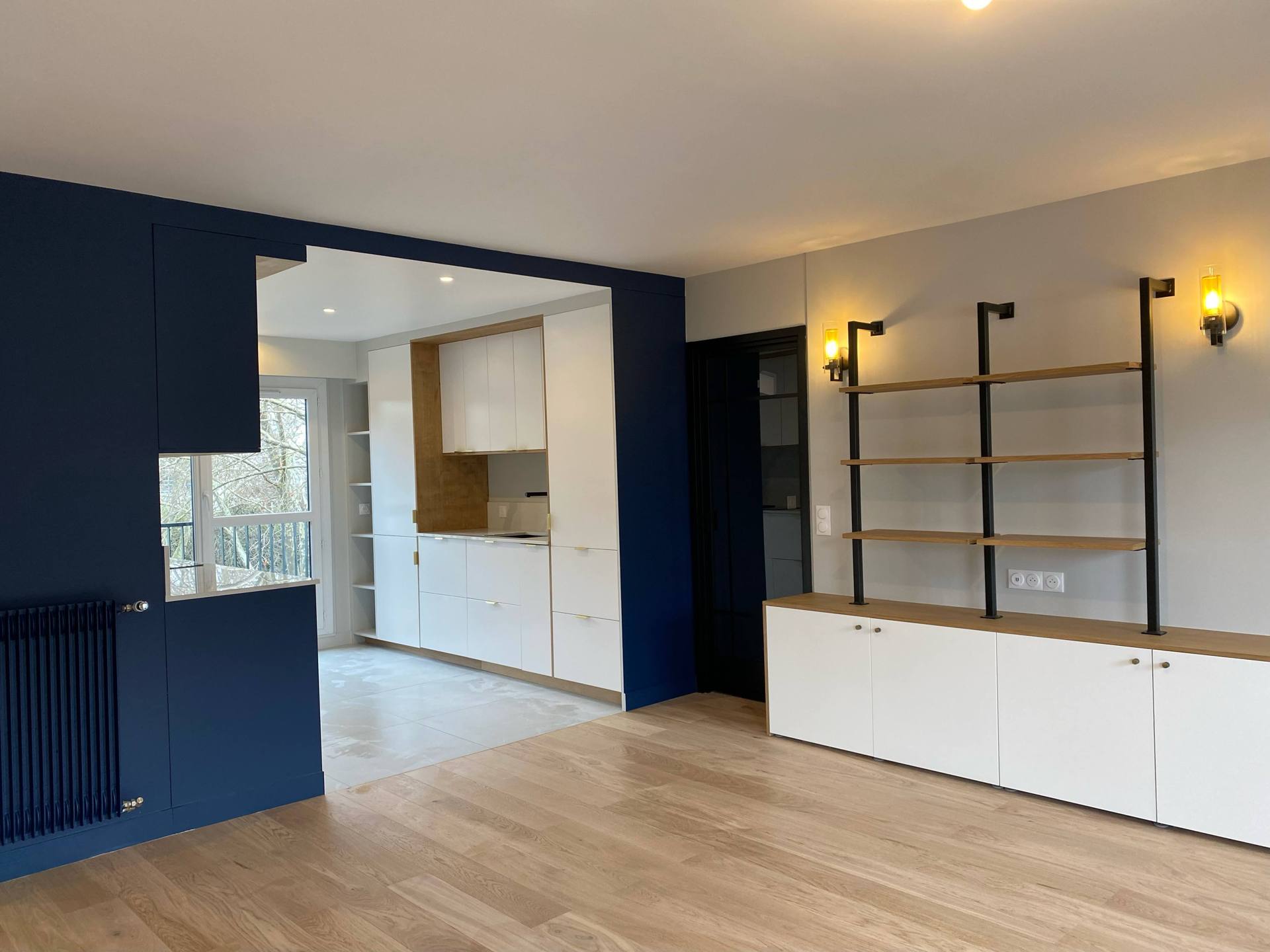 Séjour avec rangements sur mesure blancs et mur bleu